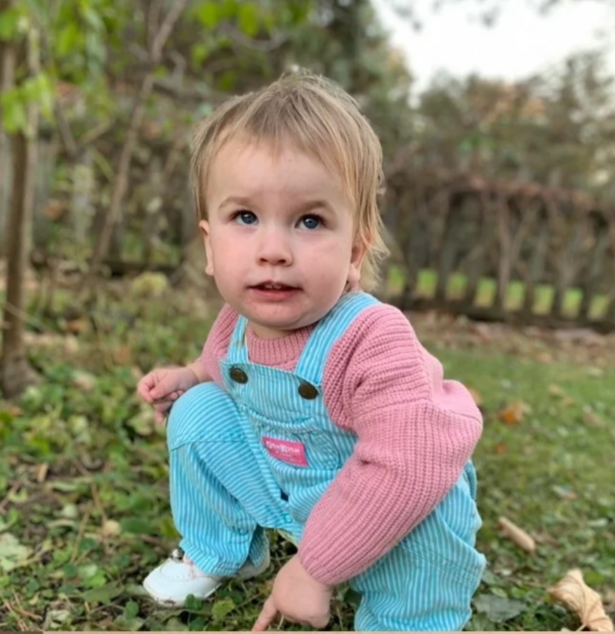 Smiling child wearing vintage kids Oshkosh B'gosh overalls with blue stripes, perfect for sustainable retro style